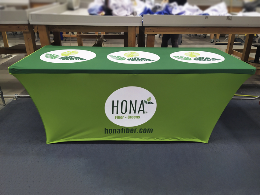 Fitted bright green/dark green tablecloth showing Hona Fiber logo.
