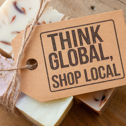 A photographic showing handmade soaps the a gift tag reading: THINK GLOBAL, SHOP LOCAL.