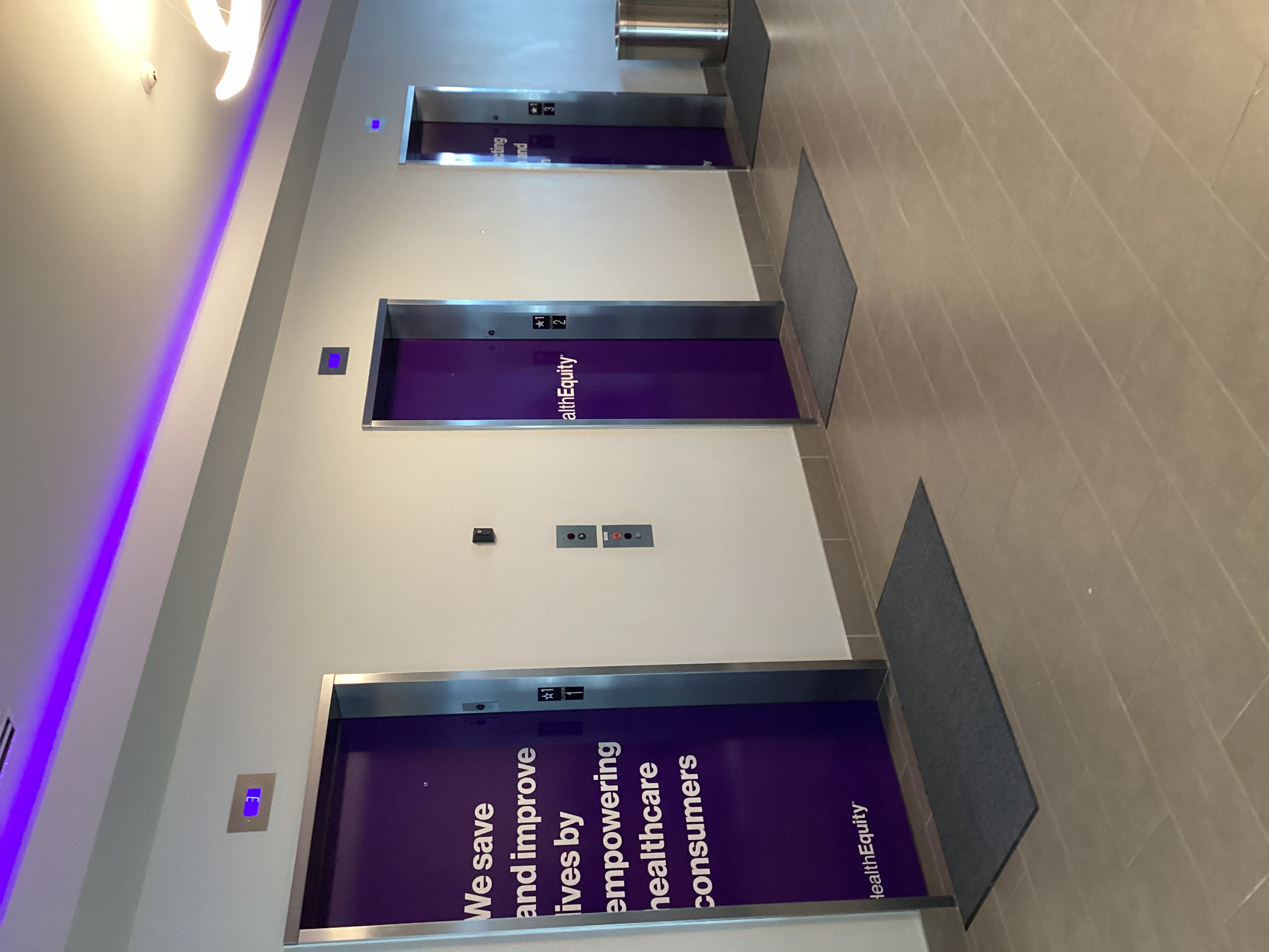 Three elevators with purple graphics on them