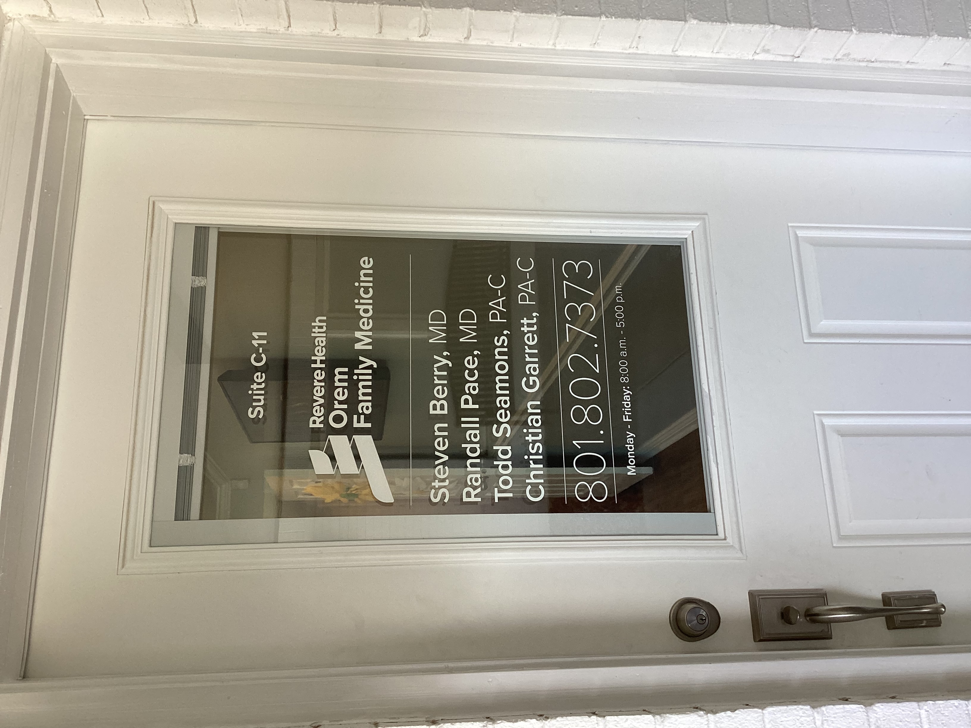 Door with a large glass window, with white vinyl lettering.
