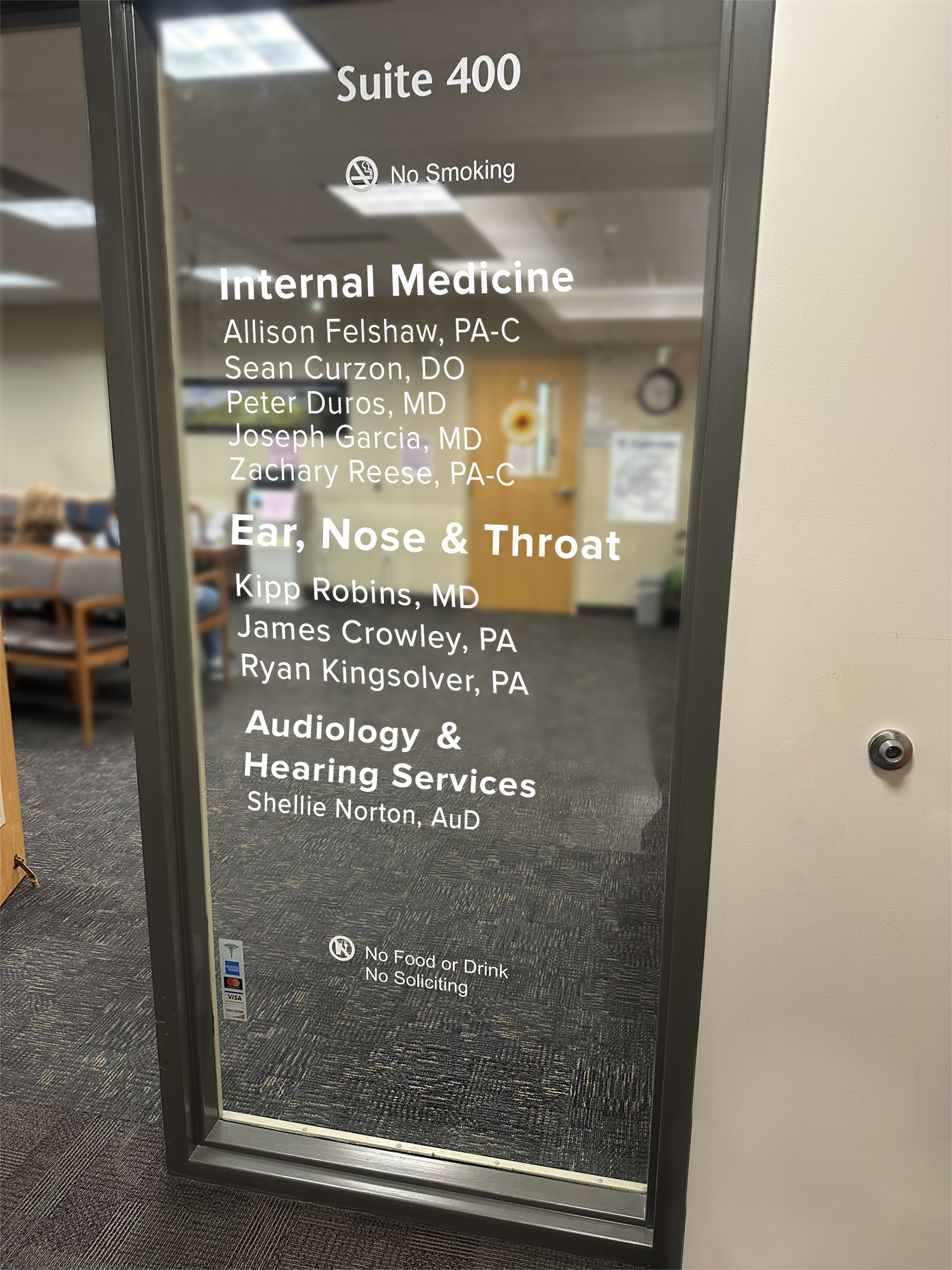 Lettering on inside office window indicating medical providers and medical designations.