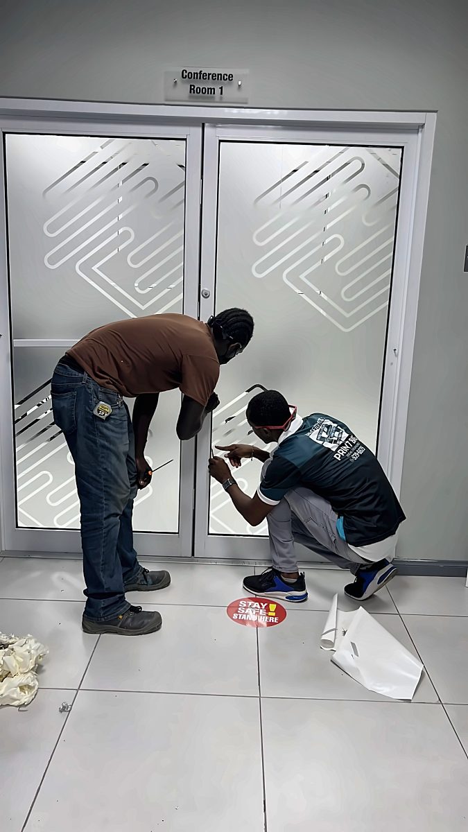 Installers fitting a patterned frosted film to glass office doors