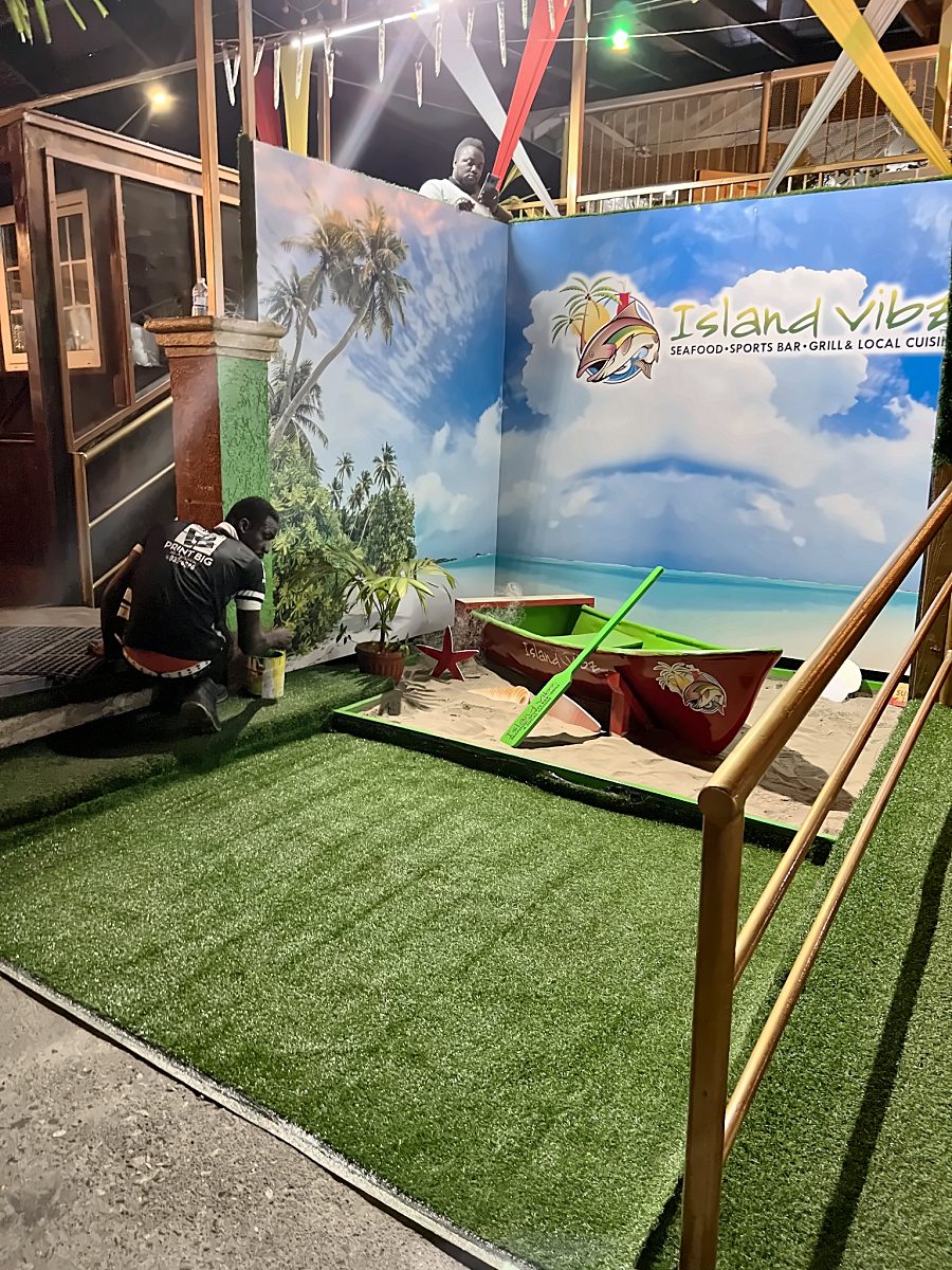 Island Vibz beach-themed photo experience with turf, boat and printed backdrop