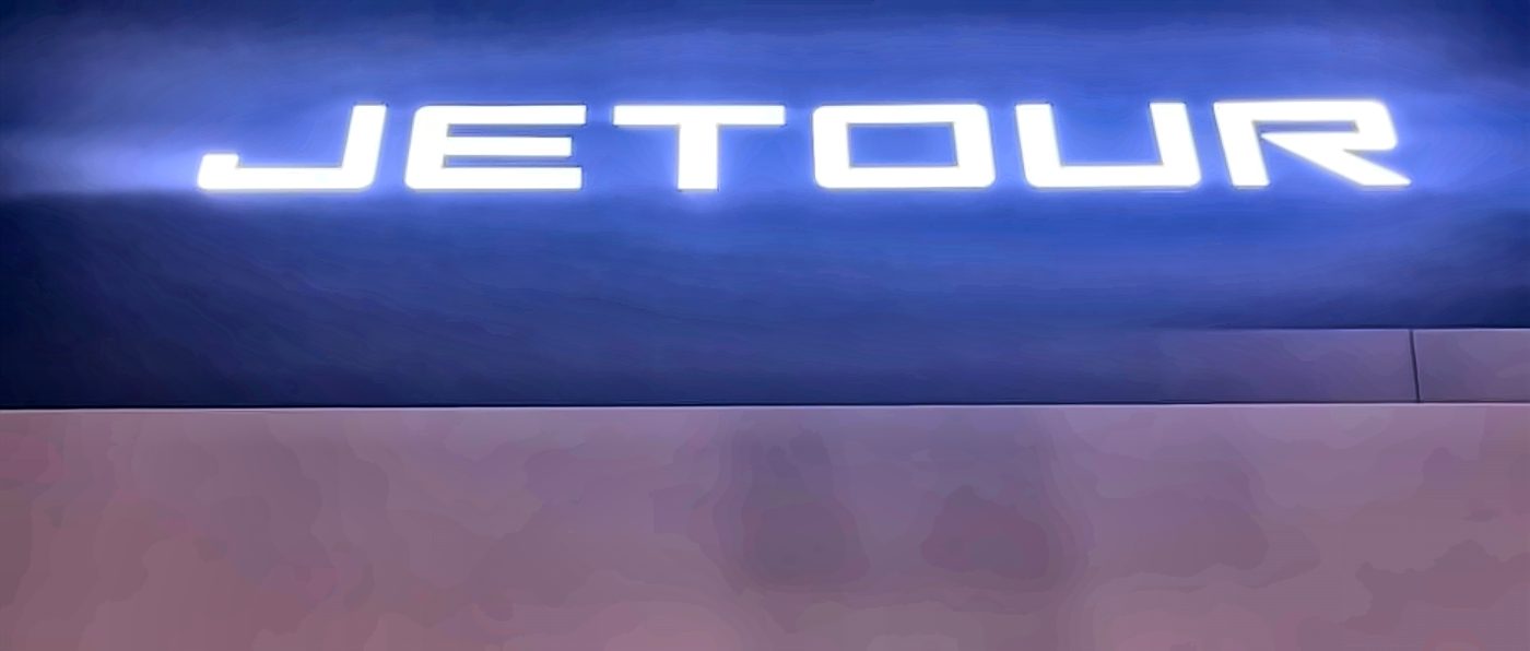 Illuminated JETOUR letters on the showroom at night