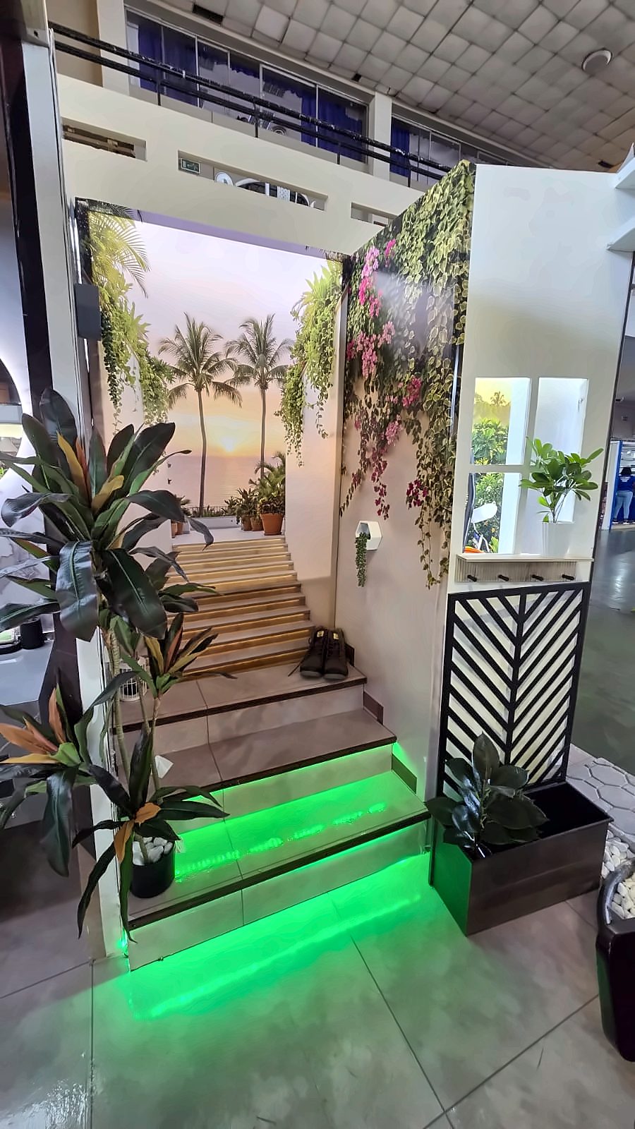 Fabricated stair with lit steps leading to a sunset perspective graphic, framed by printed vines and a cut-metal screen