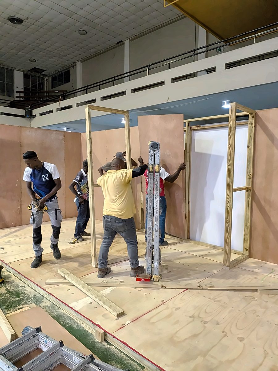 Crew fitting wall panels to the booth frame