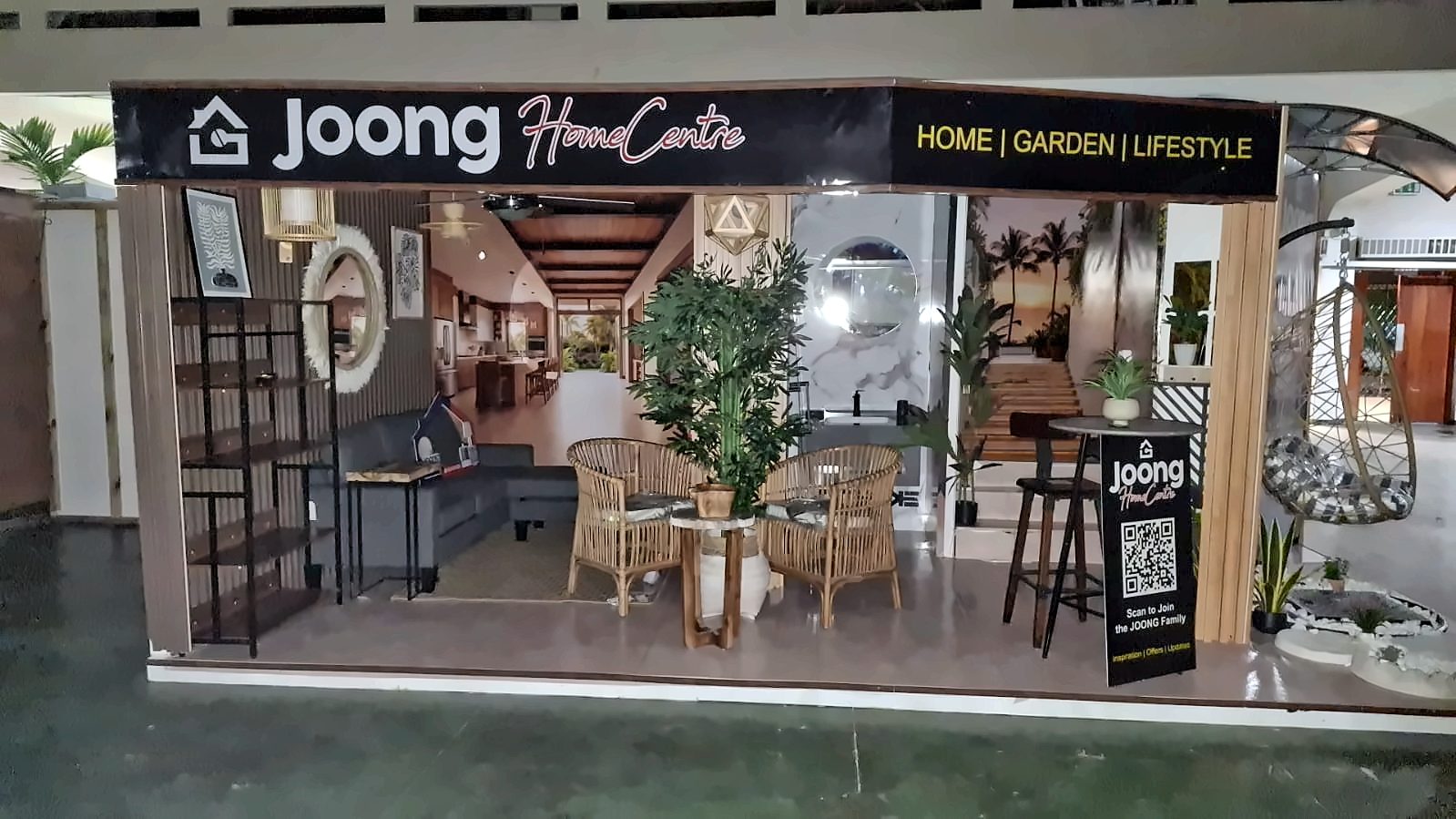 JOONG Home Centre exhibition booth by Print Big, front view: living room, bathroom, staircase and garden corner under a black JOONG fascia